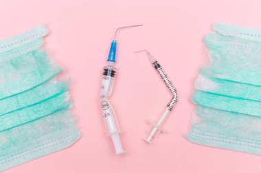 Aşı Karşıtı Hareket ve Maske Karşıtı Konsept - Kırık Tıbbi Şırınga ve Pembe Arkaplanda Yeşil Yırtık Tıbbi Maske. Salgın ve Kilitlenme Sonu - Üst Görünüm, Düz Yat