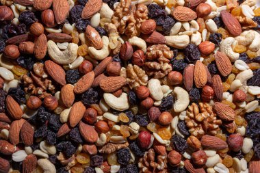 Karışık fındık, badem, ceviz, kaju, fıstık, fındık, kuru erik ve kuru üzüm. Farklı fındık karışımı. Çeşitli Fındık ve Kurutulmuş Meyvelerin Arkaplanı