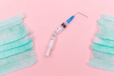 Aşı Karşıtı Hareket ve Maske Karşıtı Konsept - Kırık Tıbbi Şırınga ve Pembe Arkaplanda Yeşil Yırtık Tıbbi Maske. Salgın ve Kilitlenme Sonu - Üst Görünüm, Düz Yat