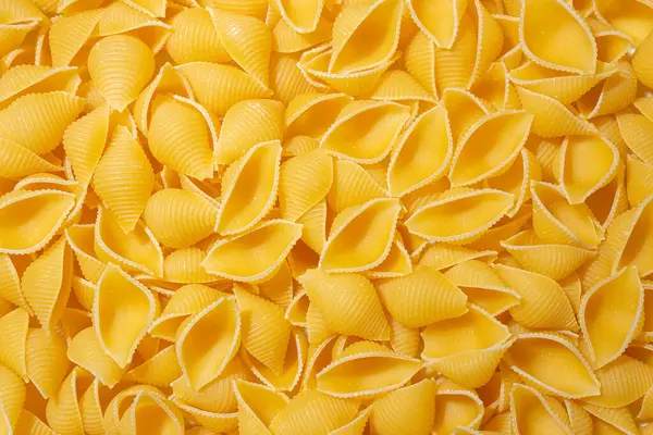 Pişmemiş Conchiglie Pasta: Konchiglie Macaroni 'nin Mutfak Tuvali, Gurme Yemekleri İçin Canlı ve Dokulu Bir Arkaplan Oluşturuyor. Kuru makarna. Raw Macaroni - Top View, Düz Yat