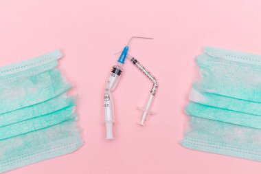 Aşı Karşıtı Hareket ve Maske Karşıtı Konsept - Kırık Tıbbi Şırınga ve Pembe Arkaplanda Yeşil Yırtık Tıbbi Maske. Salgın ve Kilitlenme Sonu - Üst Görünüm, Düz Yat