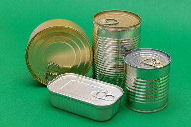 Yeşil Arkaplanda Boş Kenarlı İstiflenmiş Teneke Kutular Grubu. Konserve yiyecekler. Güvenli ve uzun vadeli yiyecek depolamak için farklı alüminyum kutular. Çelik Mühürlü Yiyecek Depolama Kutuları