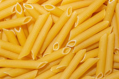 Pişmemiş Penne Rigate Makarnası: Gurme Aşçılık İçin Canlı ve Dokulu Bir Arkaplan Oluşturan Penne Makarna Mutfağı. Kuru makarna. Raw Macaroni - Top View, Düz Yat