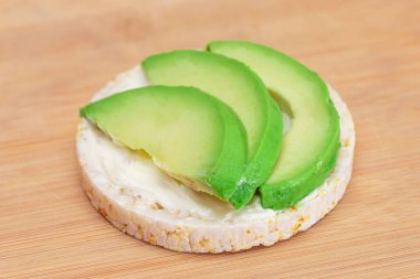 Taze Avokado ve Bambu Kesme Tahtasında Kremalı Peynirli Pirinçli Sandviç. Kolay Kahvaltı 'da. Diyet yemek. Hızlı ve sağlıklı sandviçler. Lezzetli dolgulu kızarmış ekmek. Sağlıklı Beslenme Atıştırması