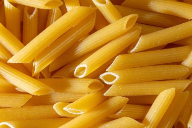 Pişmemiş Penne Rigate Makarnası: Gurme Aşçılık İçin Canlı ve Dokulu Bir Arkaplan Oluşturan Penne Makarna Mutfağı. Kuru makarna. Raw Macaroni - Top View, Düz Yat