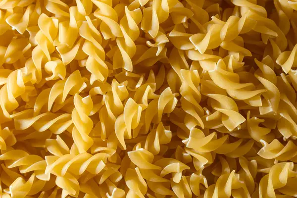 Pişmemiş Fusilli Makarna: Bir Spiral Makarna Mutfağı, Gurme Yemekleri İçin Canlı ve Dokulu Bir Arkaplan Oluşturma. Kuru makarna. Raw Macaroni - Top View, Düz Yat