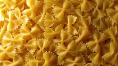 Pişmemiş Farfalle Makarnası: Gurme Aşçılığı İçin Canlı ve Dokulu Bir Arkaplan Oluşturan Papyonlu Makarna Mutfak Tablosu - Üst Görüş, Dönen. Kuru makarnaya dönüşüyor. Çiğ makarna - Döndürme