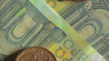 100 Euro 'luk banknotlara 20 Euro Cent madeni parası - Top View, Macro. Euro Para Birimi. Yeşil Kağıt Para. Yüz Euro 'luk banknot. İş, Finans, Para ve Tasarruf Konsepti - Yavaş Dönüşüm Sağı