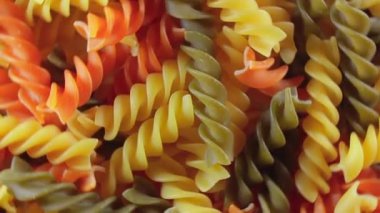 Pişmemiş Vibrant Renkli Fusilli Makarna: Büyüleyici bir rengarenk, desenli Arka plan Dönüşümlü Mutfak Kanvası. Renkli Kuru Makarnaya Dönüş. Çiğ makarna - Döndürme