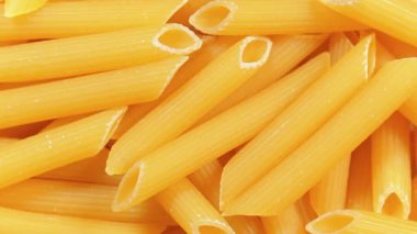Pişmemiş Penne Rigate Pasta: Penne Macaroni 'nin Mutfak Makarnası, Gurme Yemekleri İçin Canlı ve Dokulu Bir Arkaplan Oluşturma - Üst Görünüm, Döndürme. Kuru makarnaya dönüşüyor. Çiğ makarna - Döndürme
