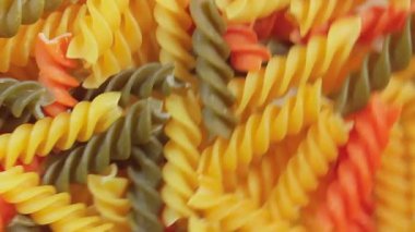 Pişmemiş Vibrant Renkli Fusilli Makarna: Büyüleyici bir rengarenk, desenli Arka plan Dönüşümlü Mutfak Kanvası. Renkli Kuru Makarnaya Dönüş. Çiğ makarna - Açısal Döndürme