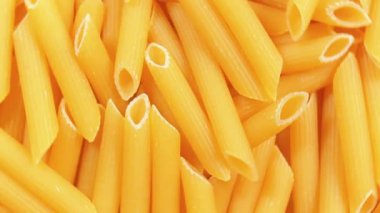 Pişmemiş Penne Rigate Pasta: Penne Macaroni 'nin Mutfak Makarnası, Gurme Yemekleri İçin Canlı ve Dokulu Bir Arkaplan Oluşturma - Üst Görünüm, Döndürme. Kuru makarnaya dönüşüyor. Çiğ makarna - Döndürme