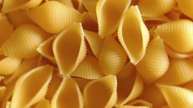 Pişmemiş Conchiglie Pasta: Konchiglie Macaroni 'nin Mutfak Tuvali, Gurme Yemekleri İçin Canlı ve Dokulu Bir Arkaplan Oluşturma - Döndürme. Kuru makarnaya dönüşüyor. Çiğ makarna - Döndürme