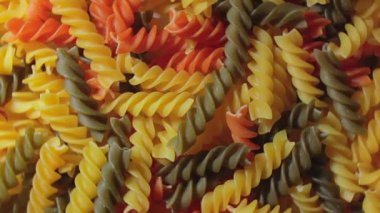 Pişmemiş Vibrant Renkli Fusilli Makarna: Büyüleyici bir rengarenk, desenli Arka plan Dönüşümlü Mutfak Kanvası. Renkli Kuru Makarnaya Dönüş. Çiğ makarna - Döndürme