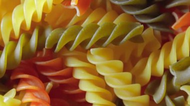 Pişmemiş Vibrant Renkli Fusilli Makarna: Büyüleyici bir rengarenk, desenli Arka plan Dönüşümlü Mutfak Kanvası. Renkli Kuru Makarnaya Dönüş. Çiğ makarna - Döndürme