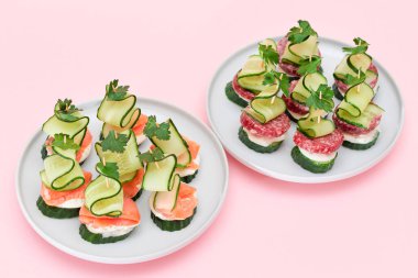 Taze somon, salam, salatalık, salatalık, yeşillik ve krem peynirli beyaz tabakta izole edilmiş kanepeler. Kolay Kahvaltı 'da. Diyet yemek. Hızlı ve sağlıklı sandviçler ve atıştırmalıklar.