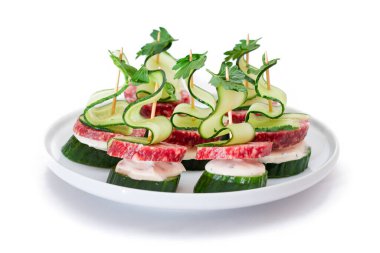 Salamlı kanepeler, salatalık, yeşillik ve krem peynirli beyaz tabakta izole edilmiş. Kolay Kahvaltı 'da. Diyet yemek. Hızlı ve sağlıklı sandviçler. Lezzetli Doldurulmuş Sağlıklı Atıştırmalıklar