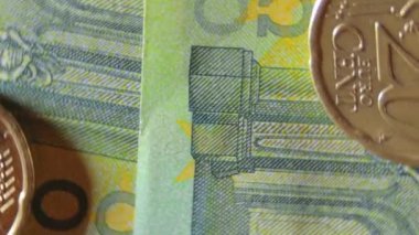 100 Euro 'luk banknotlara 20 Euro Cent madeni parası - Top View, Macro. Euro Para Birimi. Yeşil Kağıt Para. Yüz Euro 'luk banknot. İş, Finans, Para ve Tasarruf Konsepti - Dönüşüm Sola