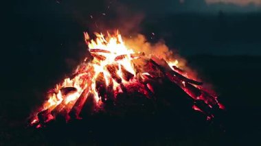 Büyük Kamp Ateşi, Sabah Erkenden veya Akşam Mavi Gök 'e Karşı Yanıyor. Ateşe odun. Uçan Kıvılcım. Seyahat ve Turizm Konsepti. Yaz 'da Devasa Şenlik Ateşi' nden Kalanlar - Statik Çekim, Zaman Aşımı