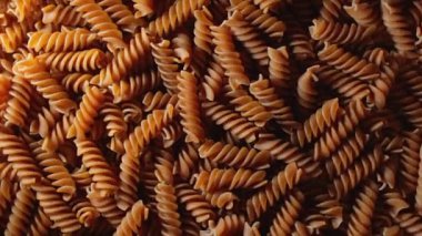 Pişmemiş Whole Grain Fusilli Makarnası: Tam Buğday Büfesi Mutfak Tablosu, Dokulu Arka plan - Üst Görünüm, Döndürme. Tam Tahıllı Bükülmüş Kuru Makarnayı Dönüştürmek. Tam buğday hamurlu makarna - Döndürme