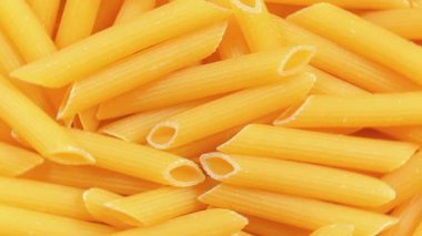 Pişmemiş Penne Rigate Pasta: Penne Macaroni 'nin Mutfak Makarnası, Gurme Yemekleri İçin Canlı ve Dokulu Bir Arkaplan Oluşturma - Üst Görünüm, Döndürme. Kuru makarnaya dönüşüyor. Çiğ makarna - Döndürme