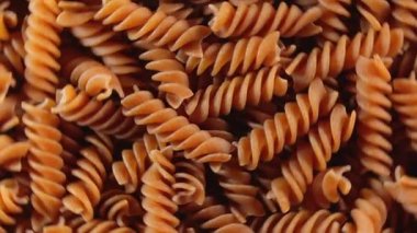 Pişmemiş Whole Grain Fusilli Makarnası: Tam Buğday Büfesi Mutfak Tablosu, Dokulu Arka plan - Üst Görünüm, Döndürme. Tam Tahıllı Bükülmüş Kuru Makarnayı Dönüştürmek. Tam buğday hamurlu makarna - Döndürme