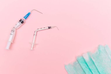 Aşı Karşıtı Hareket ve Maske Karşıtı Konsept - Kırık Tıbbi Şırınga ve Pembe Arkaplanda Yeşil Yırtık Tıbbi Maske. Salgın ve Kilitlenme Sonu - Üst Görünüm, Düz Yat