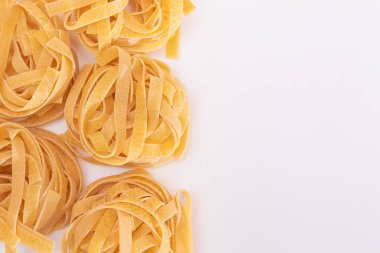 Klasik İtalyan Raw Egg Fettuccine, Beyaz Arkaplanda Kopya Spase. Kuru, bükülmemiş, pişmemiş makarna. İtalyan Kültür ve Mutfağı. Çiğ Altın Makarna Deseni