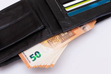 Siyah Deri Adamlar Cüzdanı 'nı 50 Euro' luk banknotlar ve Beyaz Arkaplanda İçinde Banka Kartları ile açtı. Zenginliği, başarıyı ve sosyal statüyü sembolize eden Para ve Kredi Kartlarıyla dolu bir Cüzdan