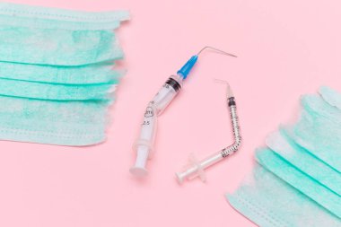 Aşı Karşıtı Hareket ve Maske Karşıtı Konsept - Kırık Tıbbi Şırınga ve Pembe Arkaplanda Yeşil Yırtık Tıbbi Maske. Salgın ve Kilitlenme Sonu - Üst Görünüm, Düz Yat