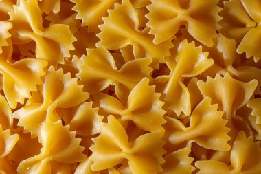 Pişmemiş Farfalle Makarnası: Gurme Aşçılık İçin Canlı ve Dokulu Bir Arkaplan Oluşturan Papyonlu Makarna Mutfağı. Kuru makarna. Raw Macaroni - Top View, Düz Yat