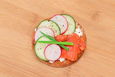 Crispy Cracker Sandwich with Salmon, Cucumber, Radish, Cottage Cheese and Green Onions on Bamboo Cutting Board. Easy Breakfast. Quick and Healthy Sandwiches. Crispbread with Tasty Filling