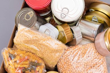 Bağış Kutusu Bedava Yemek. İçinde konserve yiyecek, mısır gevreği ve market olan bir karton kutu. Yemek rezervleri. Kriz anında acil durum gıda deposu. Ücretsiz Sosyal Yardım, Lütuf ve Bakım. Stratejik Gıda Malzemeleri