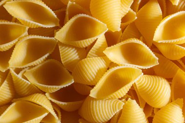 Pişmemiş Conchiglie Pasta: Konchiglie Macaroni 'nin Mutfak Tuvali, Gurme Yemekleri İçin Canlı ve Dokulu Bir Arkaplan Oluşturuyor. Kuru makarna. Raw Macaroni - Top View, Düz Yat