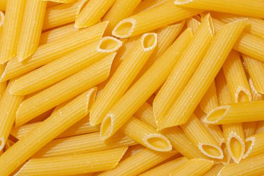 Pişmemiş Penne Rigate Makarnası: Gurme Aşçılık İçin Canlı ve Dokulu Bir Arkaplan Oluşturan Penne Makarna Mutfağı. Kuru makarna. Raw Macaroni - Top View, Düz Yat