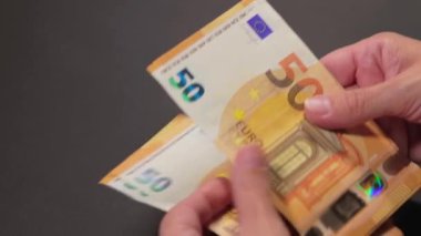 Elde Para Saymak. Avrupa Birliği Parası. Siyah Masa 'ya 50 Euro' luk banknotlar sayan Beyaz Kadın - Yakın plan. Turuncu Kağıt Nakit. Elde Elli Euro. Gelir, Tasarruf ve Harcama Konsepti