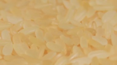 Dry Uncooked Parboiled Rice Rotating - Macro. Scattered Raw Long Grain Rice - Close-Up. Asian Cuisine and Culture. Healthy Eating Ingredients. Diet Food