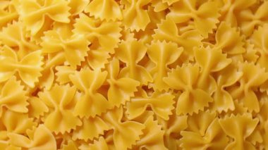 Pişmemiş Farfalle Makarnası: Gurme Aşçılığı İçin Canlı ve Dokulu Bir Arkaplan Oluşturan Papyonlu Makarna Mutfak Tablosu - Üst Görüş, Dönen. Kuru makarnaya dönüşüyor. Çiğ makarna - Döndürme