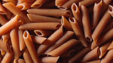 Pişmemiş tam tahıllı Penne Rigate Makarnası: Bütünüyle Buğday Makarnası Mutfağı, Dokulu Arka plan - Üst Görünüm, Döndürme. Tam Tahıllı Kurutulmuş Makarna. Tam buğday hamurlu makarna - Döndürme
