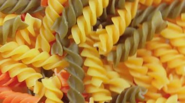 Pişmemiş Vibrant Renkli Fusilli Makarna: Büyüleyici bir rengarenk, desenli Arka plan Dönüşümlü Mutfak Kanvası. Renkli Kuru Makarnaya Dönüş. Çiğ makarna - Yan Döndürme