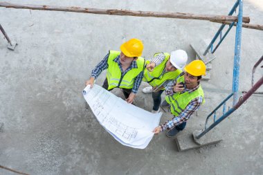 Top view of Asian engineer or Young Female Architect put on a helmet for safety and talk with a contractor on a construction building factory project, Concept of Teamwork, Leadership concept.
