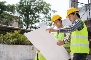 Asyalı mühendis ya da genç bayan mimar güvenlik için bir kask taktı ve bir inşaat fabrikası projesi için müteahhitle konuştu: Takım çalışması kavramı, liderlik kavramı..