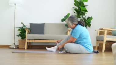 Asian senior woman stretching for exercise and workout at home. Active mature woman doing stretching exercise in living room. Exercise Active and healthy for older, elder, and senior concept.