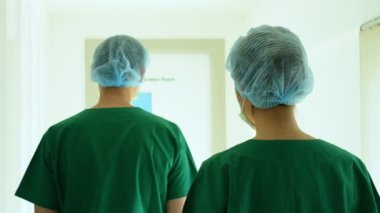 Two asian surgeon Doctors with medical mask walking to operation room for plastic scrubs, Concept of medical, beauty Sacraments, and health care.