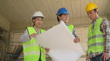 Bir grup Asyalı mühendis ya da genç bayan mimar güvenlik için bir kask taktılar ve bir inşaat fabrikası projesi için müteahhitle görüştüler: Takım çalışması kavramı, liderlik kavramı..