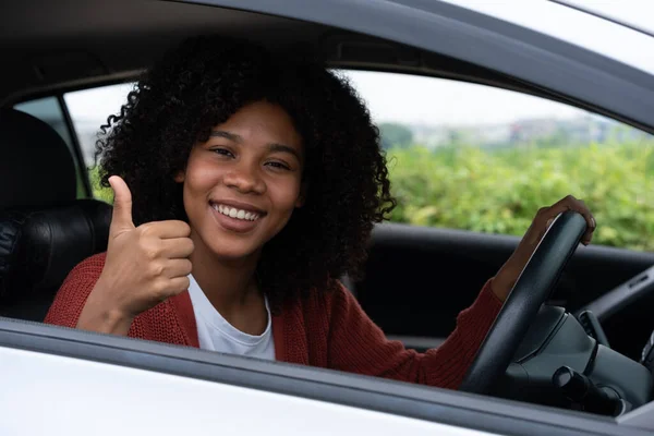 若い女性の半分のアジアの半分アフリカは 新しい現代の車の中に親指を表示します パスドライバー免許試験後の若い女性の興奮最初の道路の旅 新しい車を手に入れた後は気分がいい — ストック写真