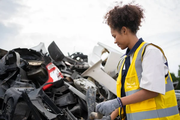 Mechanical woman owner small business inspecting standing in the car junkyard, Dirty male repairman choosing spare parts on car junkyard, Used of vehicle part for recycling in the scrap yard garage.