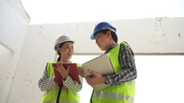 Asyalı mühendis ya da genç bayan mimar güvenlik için bir kask taktı ve bir inşaat fabrikası projesi için müteahhitle konuştu: Takım çalışması kavramı, liderlik kavramı..