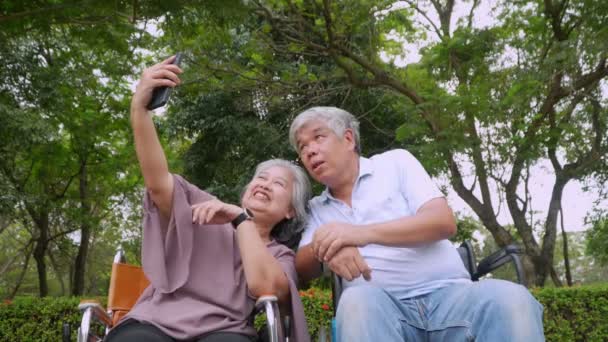 Счастливая Азиатская Пожилая Пара Сидит Инвалидной Коляске Использовать Смартфон Сфотографироваться — стоковое видео