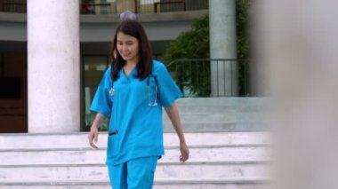Mavi önlük giyen, kendine güvenen, mutlu ve gülümseyen Asyalı doktor ya da hemşire portresi..